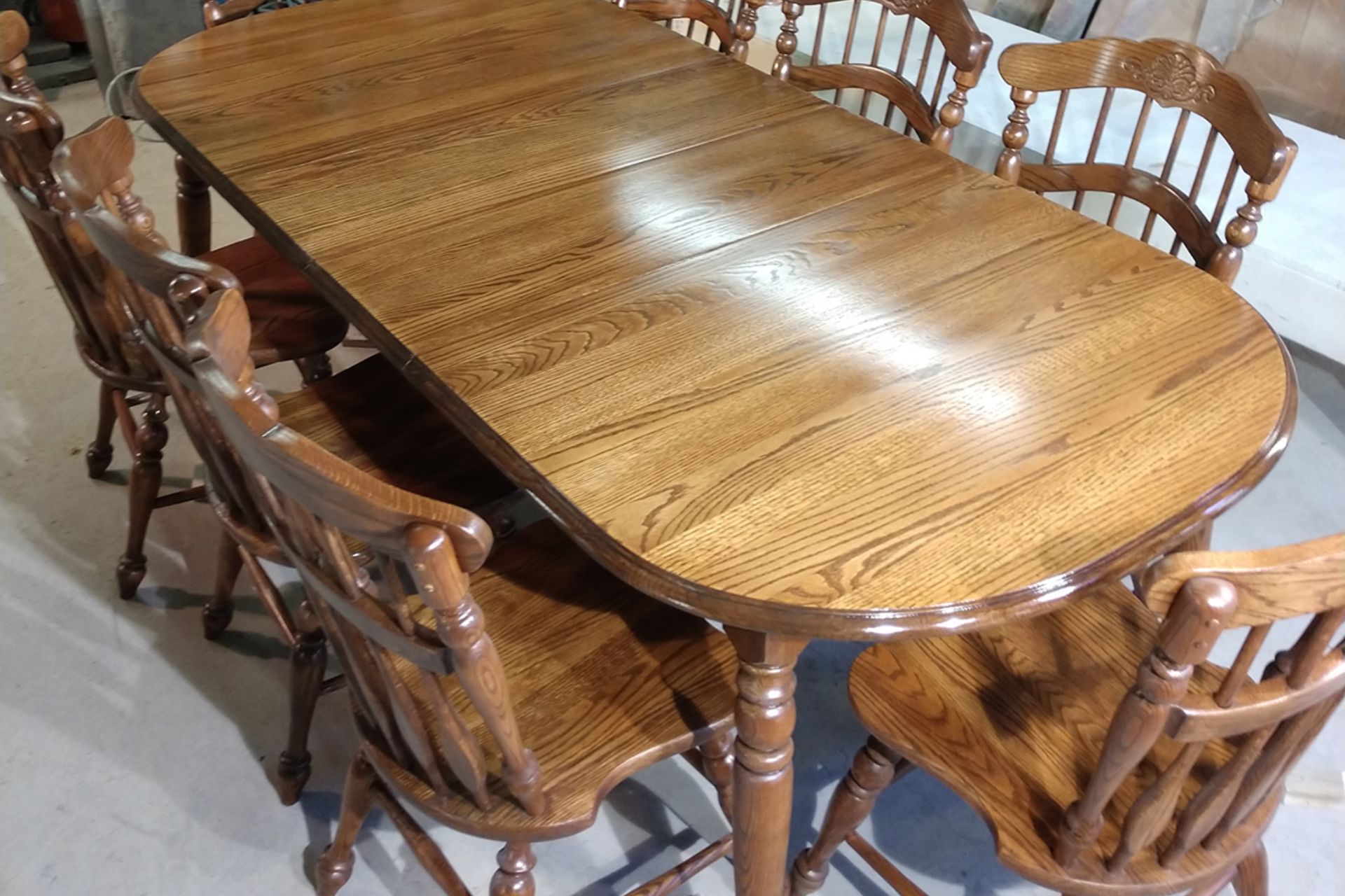 A large wooden table surrounded by six matching chairs, set in a well-lit dining area.