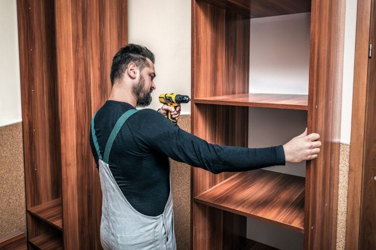 A craftsman focused on restoring a wooden cabinet as part of a furniture repair service.