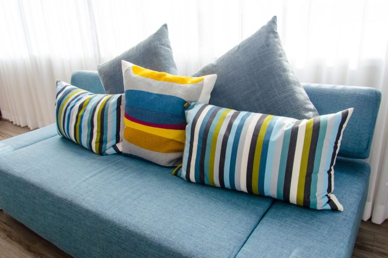 A blue couch adorned with various colorful pillows, creating a vibrant and inviting seating area.