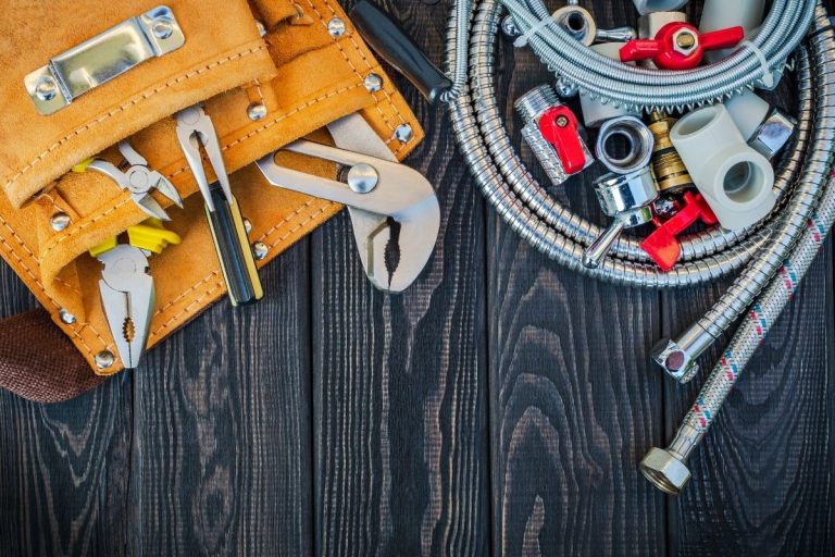 A variety of tools arranged on a wooden table, including wrenches, screwdrivers, and pliers, showcasing a workspace setup.